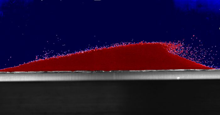 Fot. Wydma z eksperymentu zrobiona ze szklanych kuleczek. Widać, jak ruch wody gwałtownie wwiewa je po nawietrznym zboczu wydmy. Źródło: Karol Bacik, Nathalie Vriend