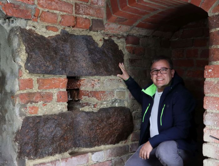 Dr Dariusz Brykała przy kamieniach młyńskich wmurowanych w ścianę  wieży zamku kapituły warmińskiej w Olsztynie (fot. Piotr Czubla)