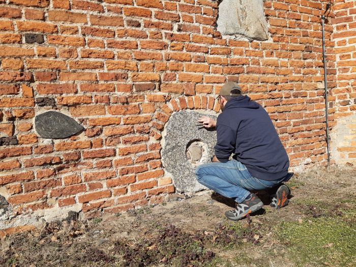 Dr Maciej Prarat (UMK w Toruniu) podczas poboru próbek zaprawy wokół kamienia młyńskiego do dalszych analiz laboratoryjnych (fot. Dariusz Brykała)