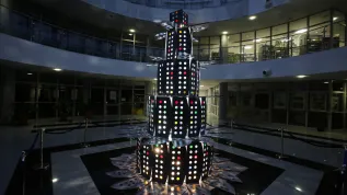 Olsztyn, 09.12.2025. Nietypowa świąteczna choinka w Bibliotece Uniwersytetu Warmińsko-Mazurskiego w Olsztynie, 9 bm. Biblioteka słynie z oryginalnych choinek. W tym roku do budowy drzewka wykorzystano metalowe ograniczniki do stolików, które w przeszłości oddzielały poszczególne stanowiska dla studentów korzystających z czytelni. Użyto też kolorowej folii, która podświetlona imituje bombki choinkowe. PAP/Tomasz Waszczuk