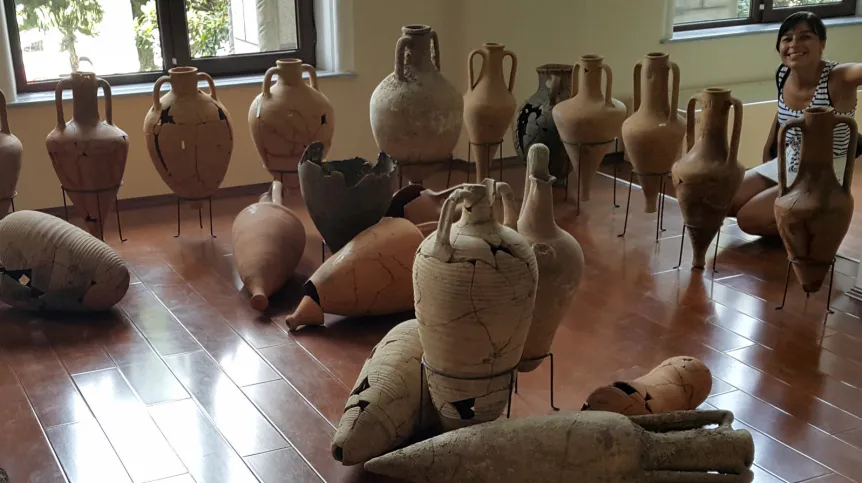 The author of the project surrounded by amphorae from the eastern part of the Mediterranean, Archaeological Museum in Batumi. Photo by M. Marciniak