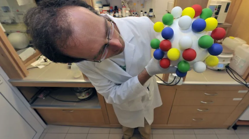 Dr inż. Rafał Szmigielski z Instytutu Chemii Fizycznej Polskiej Akademii Nauk (IChF PAN) w Warszawie prezentuje poglądowy model drobiny pyłu zawieszonego. Źródło: IChF PAN, Grzegorz Krzyżewski