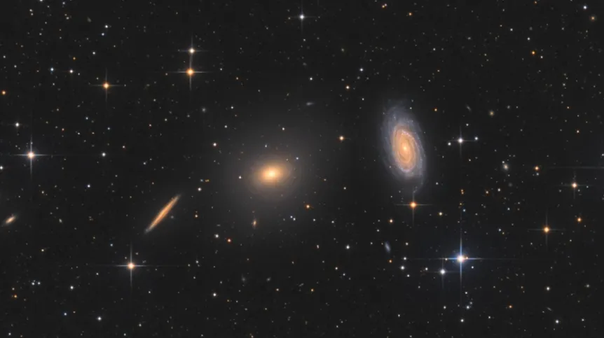 Na zdjęciu widać galaktykę eliptyczną NGC 5982 (w centrum) oraz galaktykę spiralną NGC 5985 (po prawej). Okazuje się, ze te dwa rodzaje galaktyk zachowują się inaczej w przypadku nadmiarowej grawitacji w swoich zewnętrznych rejonach. Źródło: Bart Delsaert (www.delsaert.com).