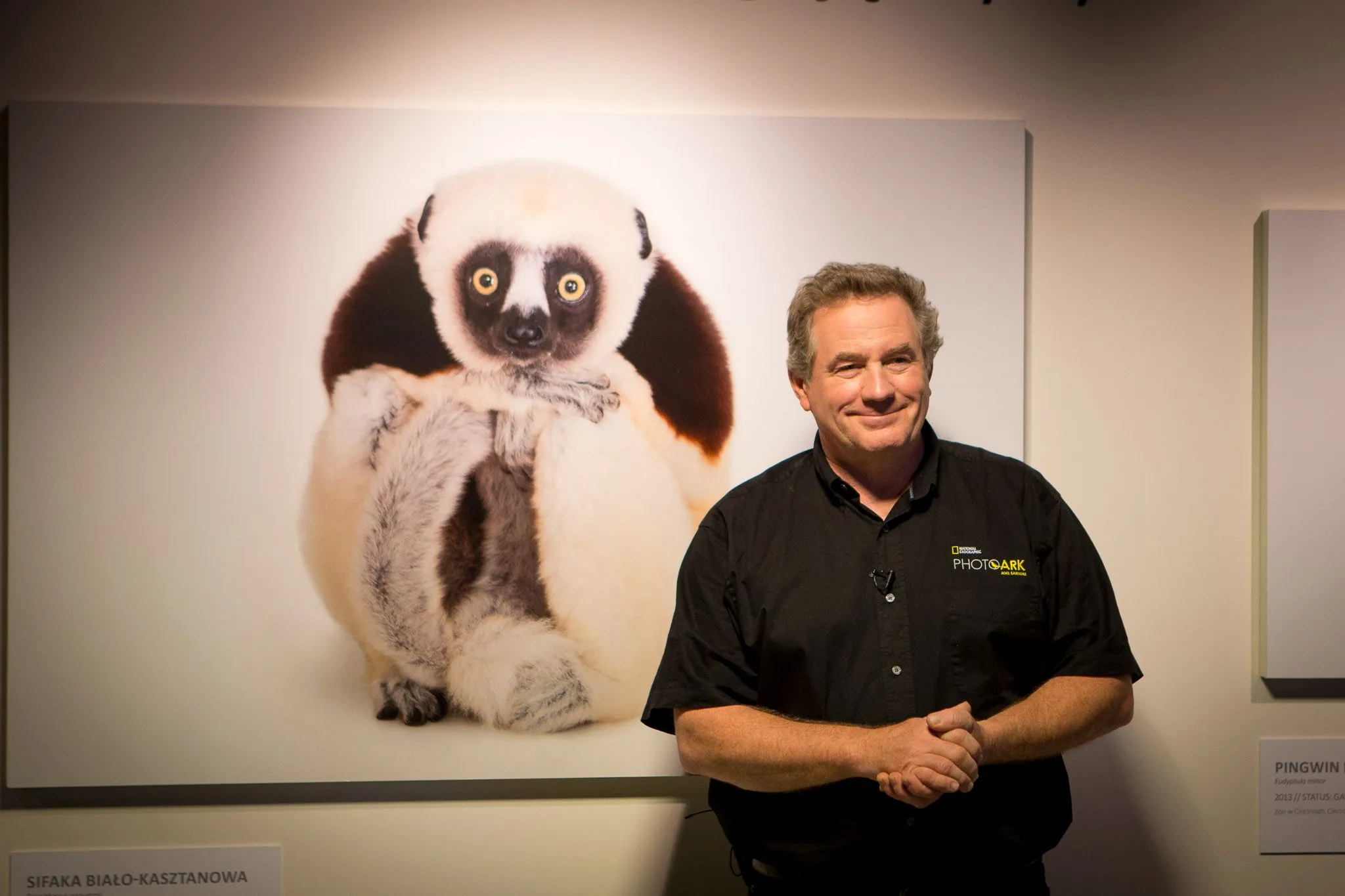 Joel Sartore, w tle jedna z jego prac. Fot. materiały prasowe National Geographic