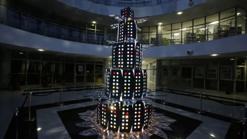 Olsztyn, 09.12.2025. Nietypowa świąteczna choinka w Bibliotece Uniwersytetu Warmińsko-Mazurskiego w Olsztynie, 9 bm. Biblioteka słynie z oryginalnych choinek. W tym roku do budowy drzewka wykorzystano metalowe ograniczniki do stolików, które w przeszłości oddzielały poszczególne stanowiska dla studentów korzystających z czytelni. Użyto też kolorowej folii, która podświetlona imituje bombki choinkowe. PAP/Tomasz Waszczuk